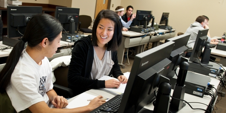 Two female students in a computer lab.