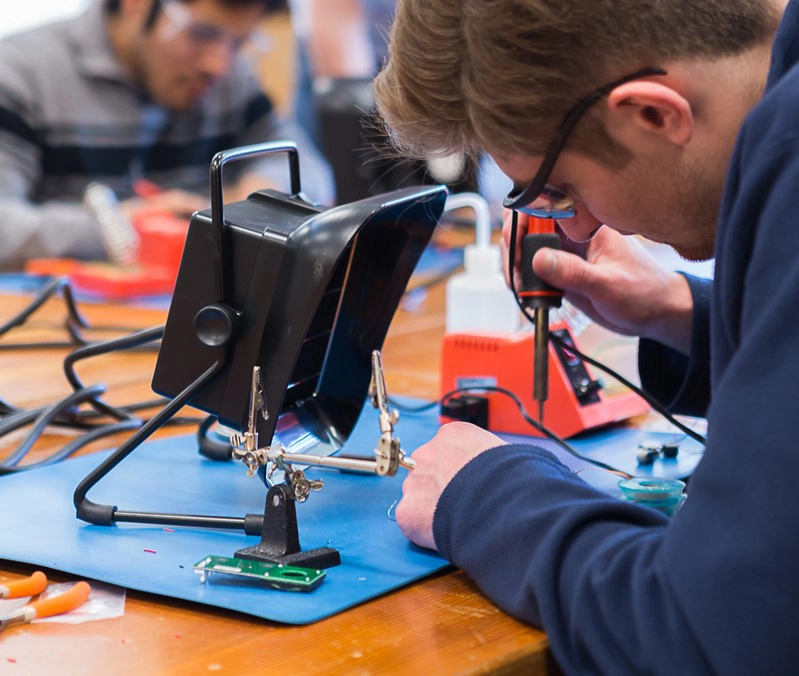 Engineering students soldering electrical components.